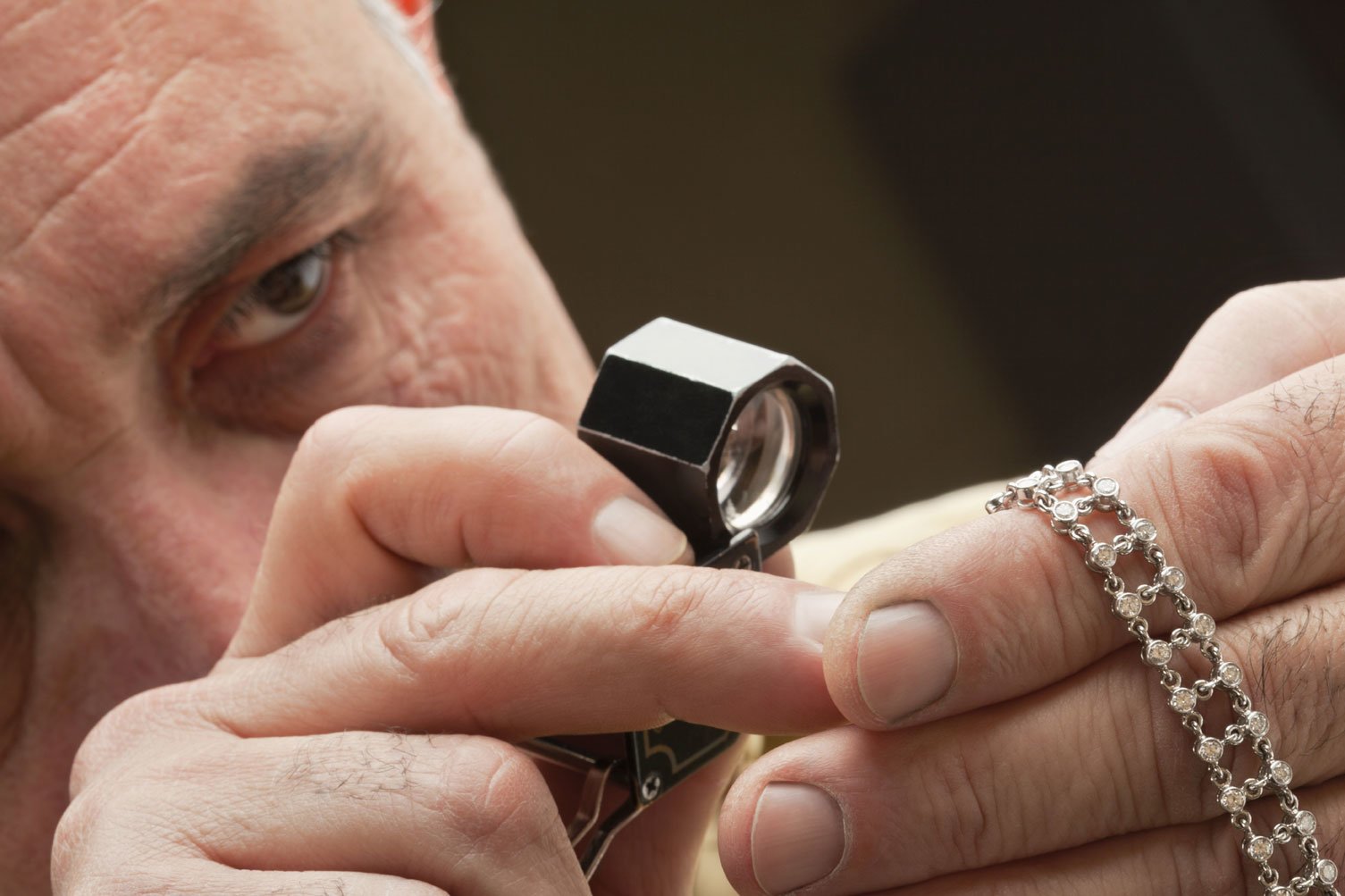 Jeweler appraising a bracelet by looking through a loupe
