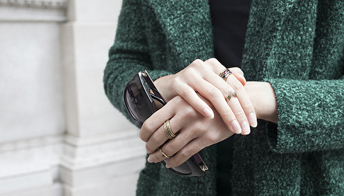 Woman wearing stacks of delicate rings and thin bands.
