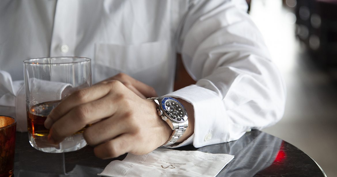 Man wearing a Rolex GMT Batman while holding a cocktail