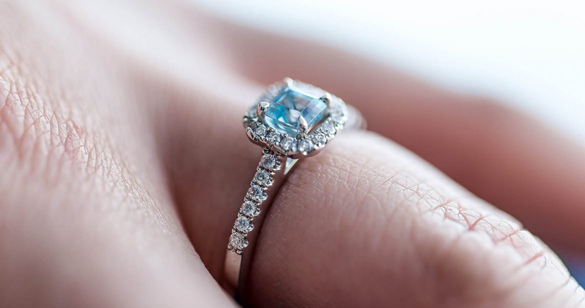 Engagement ring with blue center stone, on finger